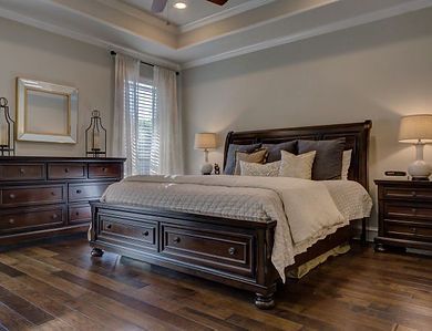A traditional bedroom featuring a dark wood bed with storage drawers, matching dresser and nightstand, and hardwood floors.