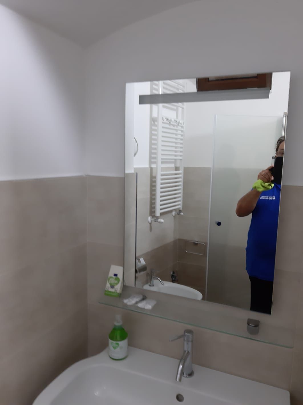 Un uomo con una camicia blu si sta scattando una foto allo specchio del bagno