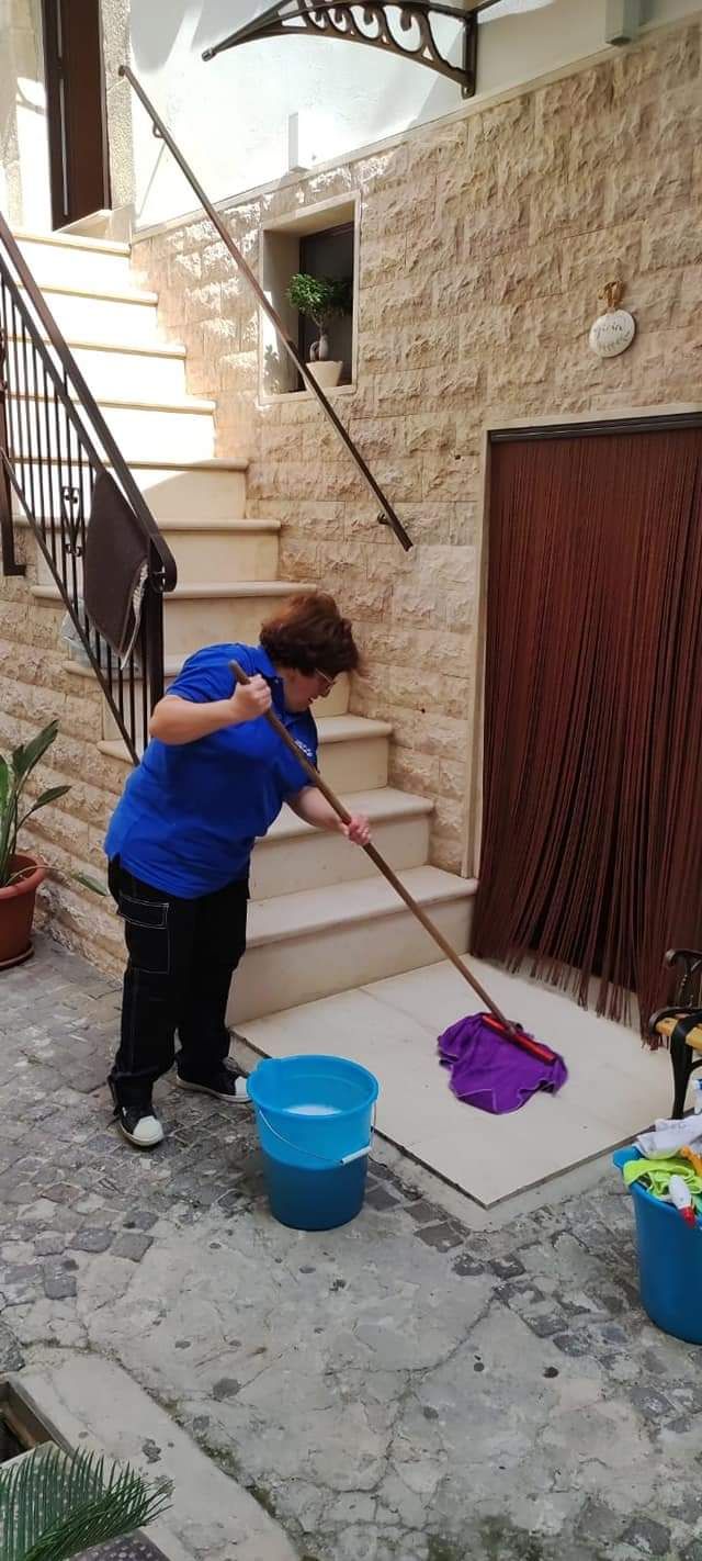 Una donna sta lavando il pavimento davanti a una scala.