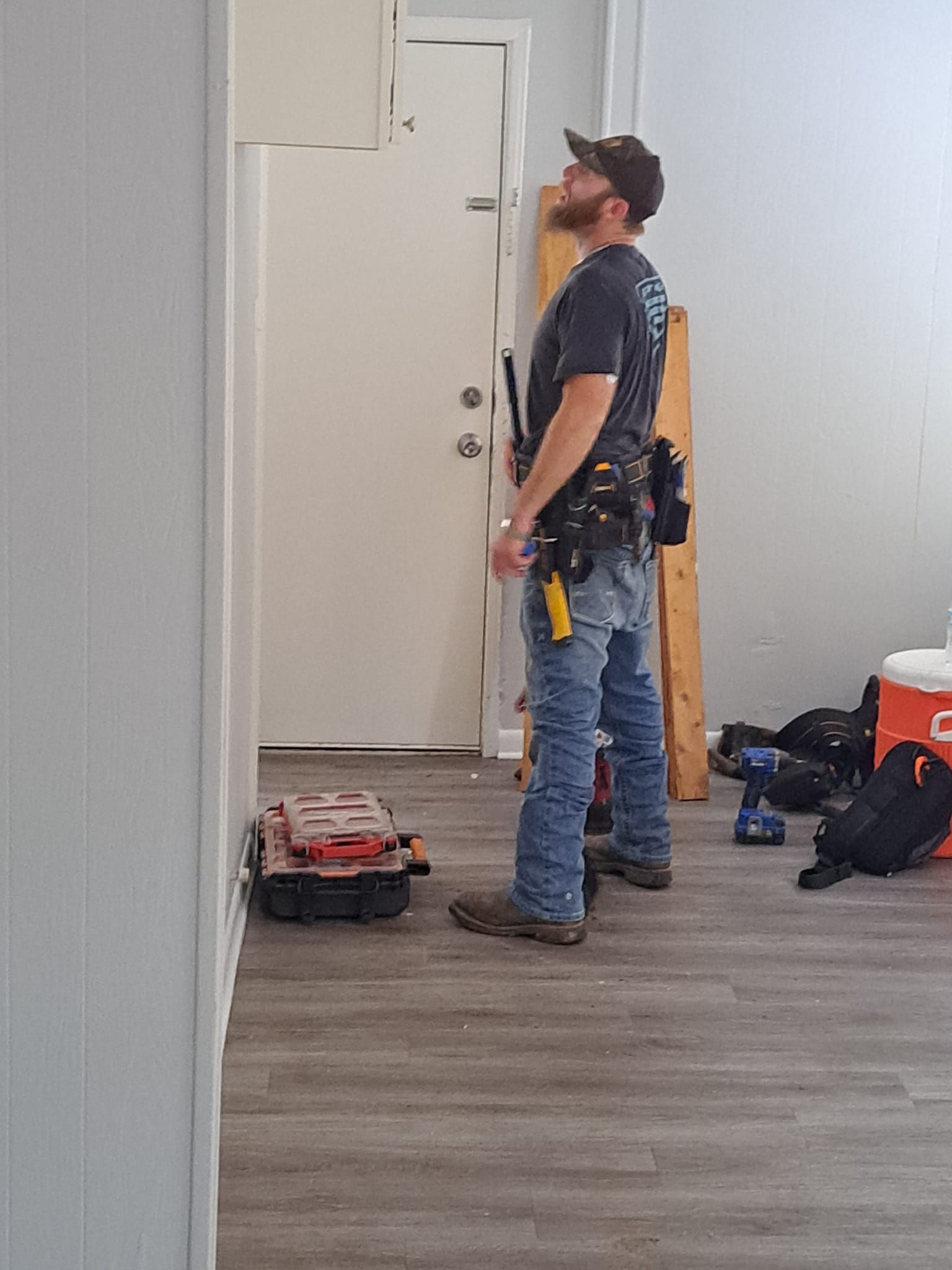 Worker standing in a room looking up, with tools and equipment on the floor nearby.