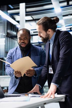 Two professionals reviewing documents at a desk in a modern office