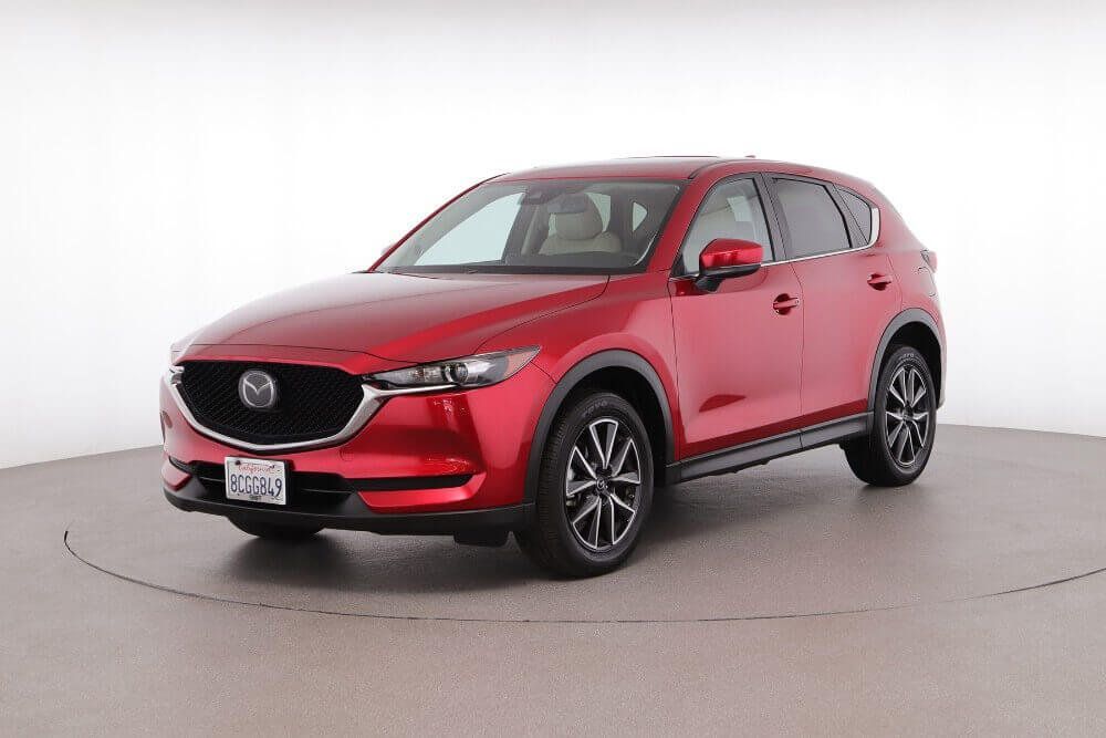 Red Mazda SUV on a studio turntable, shown in front three-quarter view