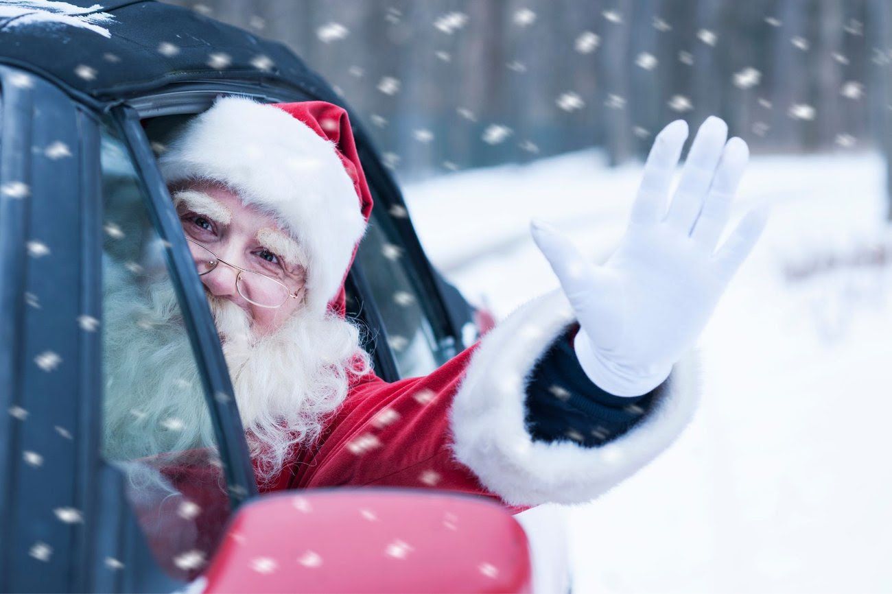 Santa waving from a car window in a snowy landscape