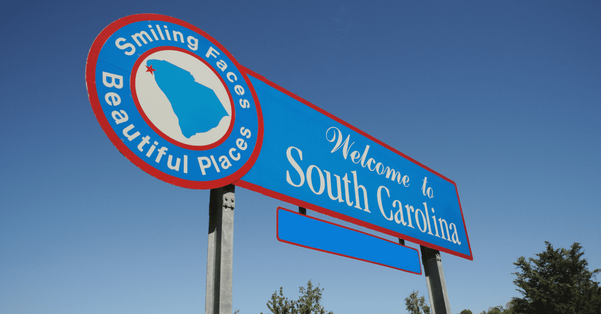 South Carolina welcome sign with blue sky, reading “Smiling Faces, Beautiful Places” and “Welcome to South Carolina”