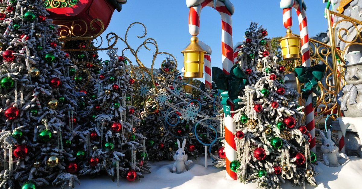 Outdoor Christmas decorations with candy cane poles, colorful ornaments, and snow-covered bushes