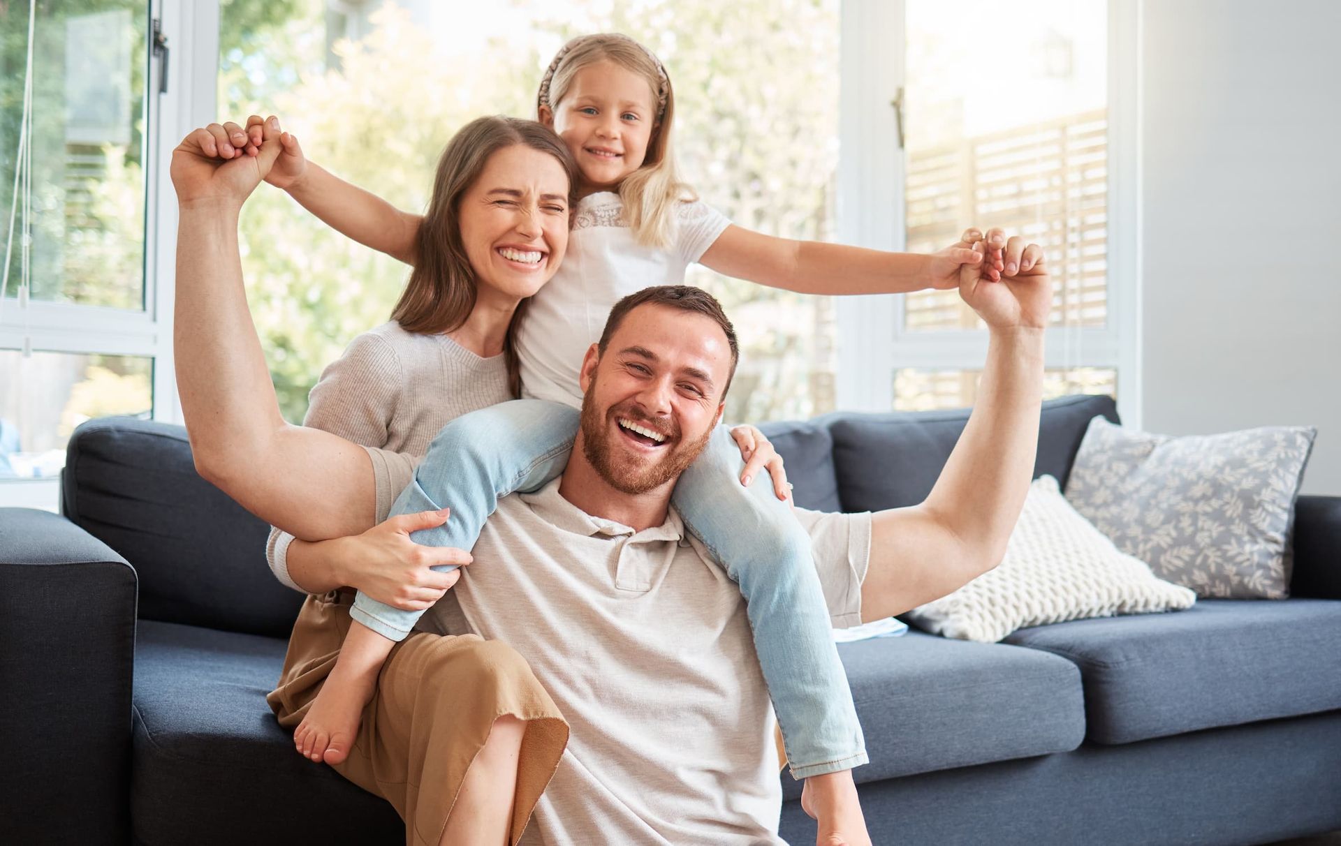 Smiling family playing on a couch in a bright living room