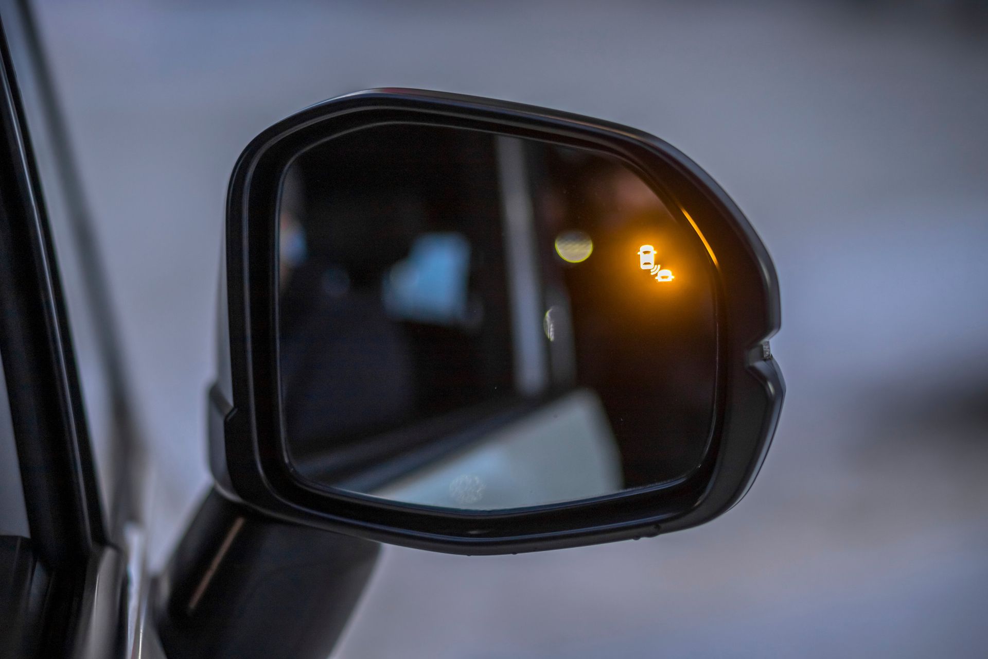 Car side mirror with amber indicator light reflecting the road