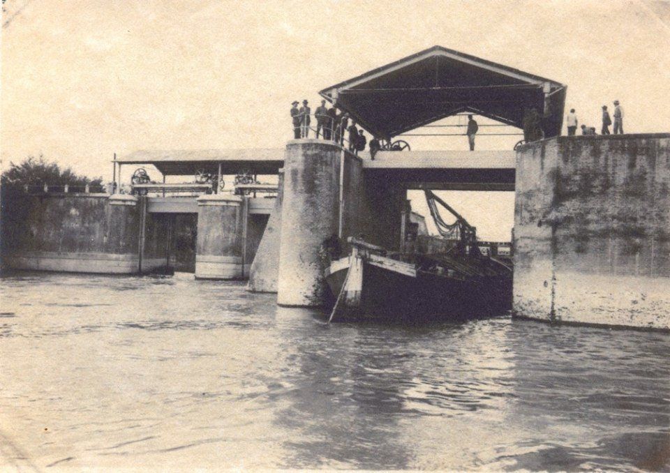 Un ponte levatoio su un fiume, con una barca che lo attraversa e persone in piedi sul ponte.