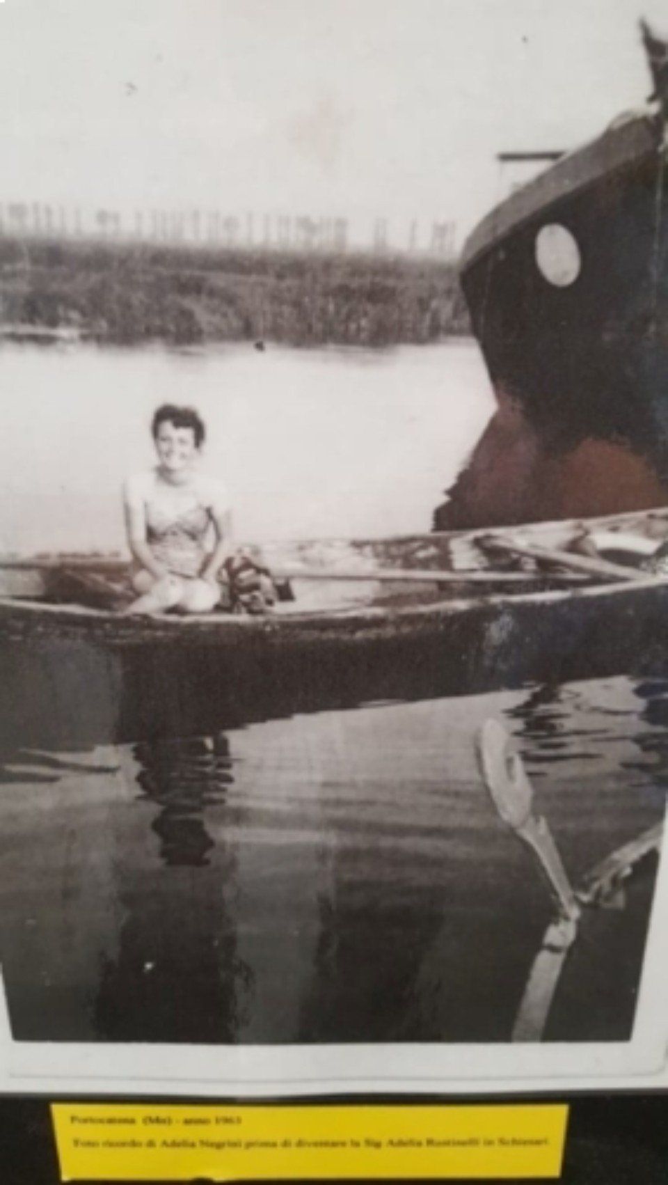 Una persona seduta in una piccola barca a remi su acque calme accanto a una nave più grande.