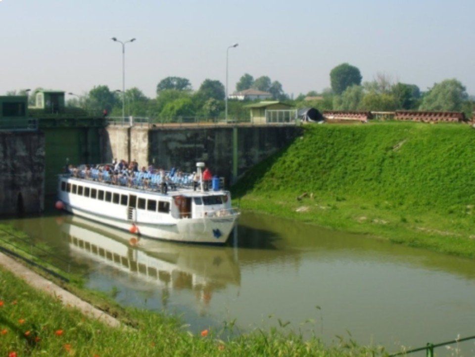 Barca passeggeri bianca che attraversa una chiusa del canale con rive verdi e erbose