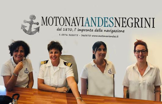 Quattro membri dello staff in uniforme bianca sono in piedi dietro un bancone di legno presso il ristorante Motonavi Andes Negrini.