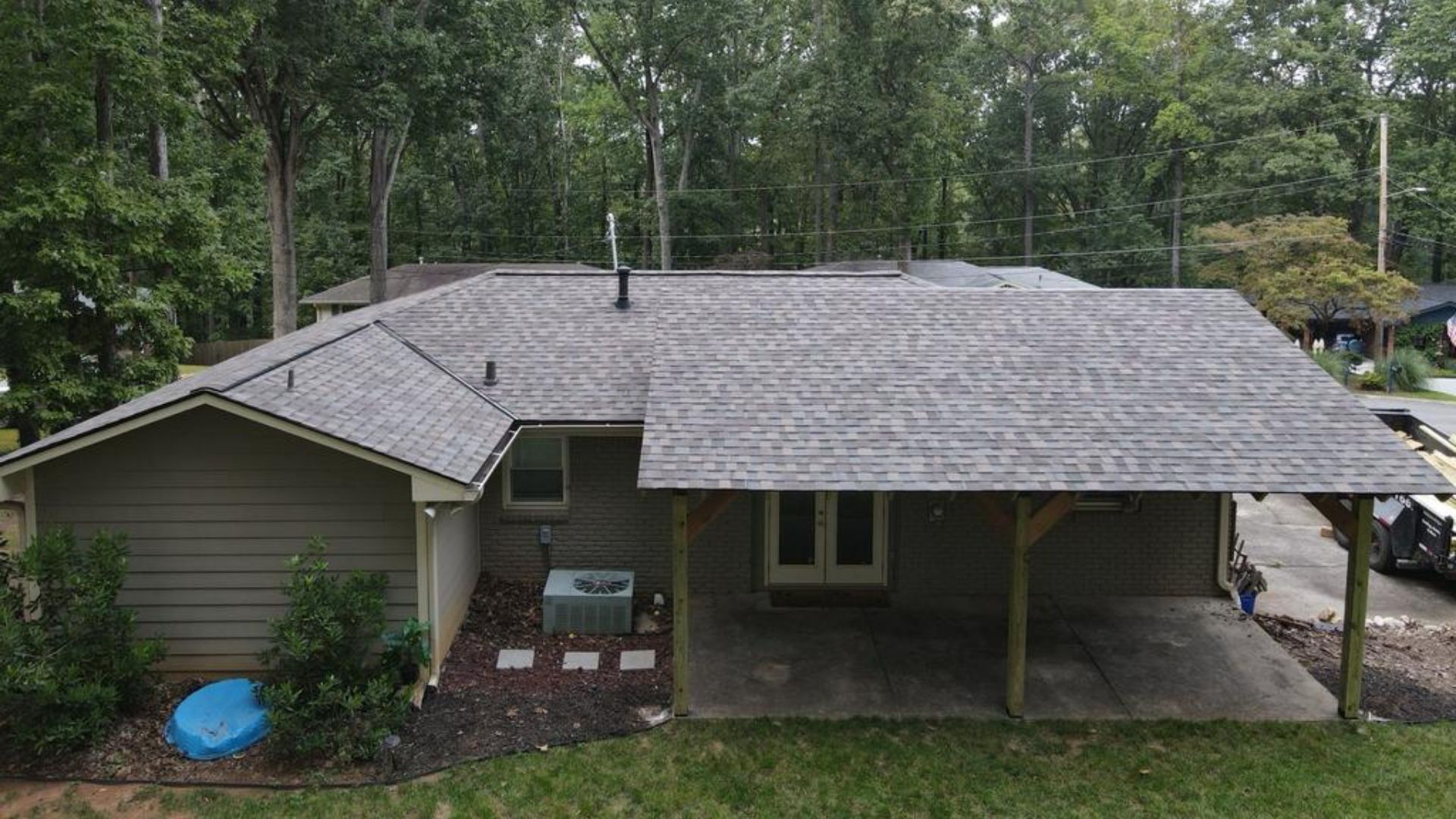 Dark green cabin with wraparound porch and wooden steps with a new roof in Carrollton Ga