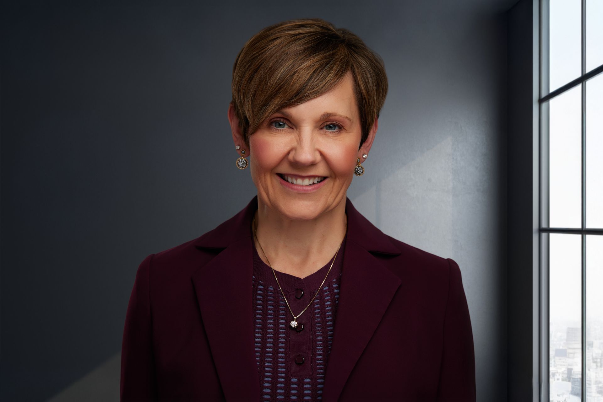 A woman wearing a striped shirt and earrings is smiling for the camera.