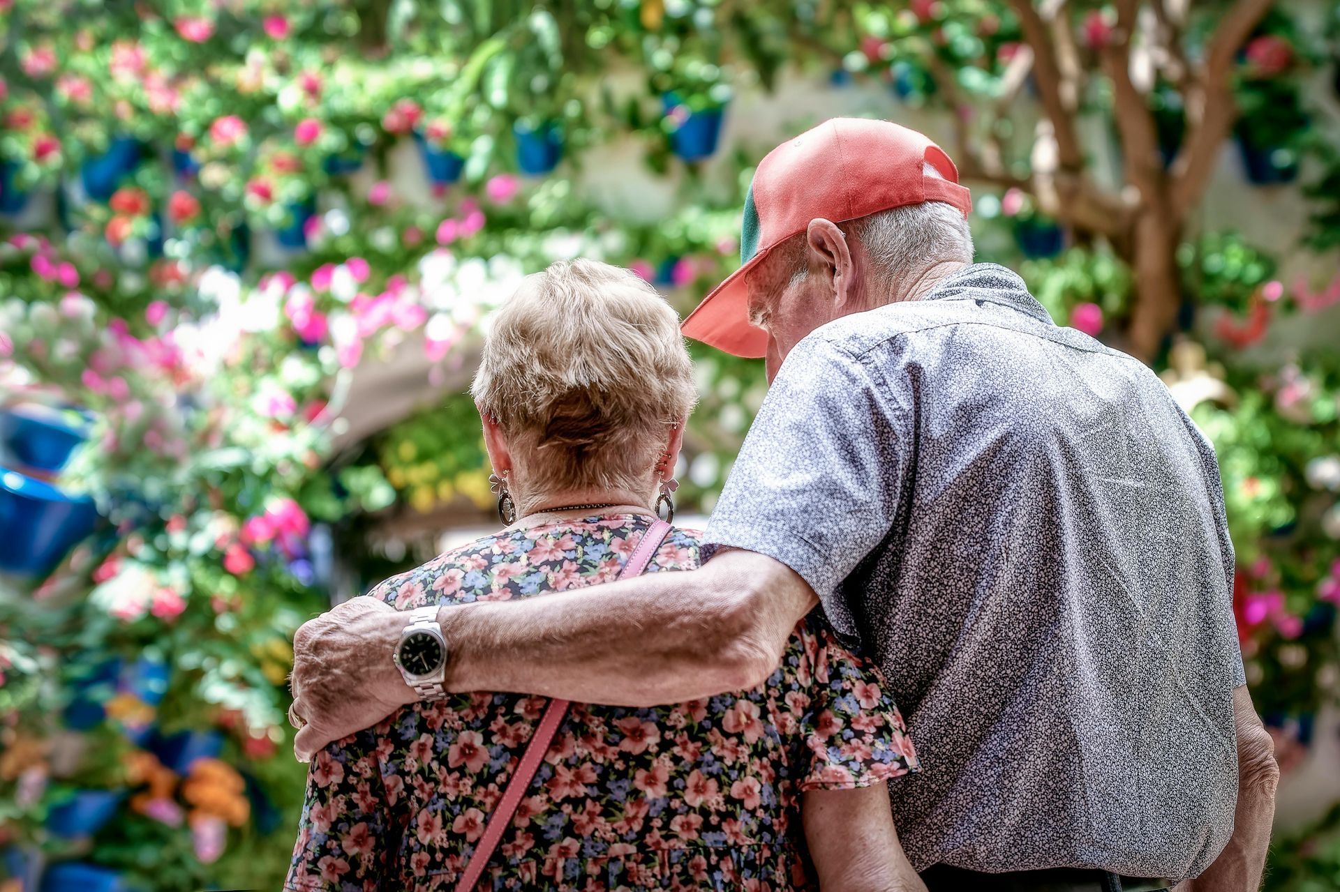 Two people standing arm in arm in a colorful flower garden