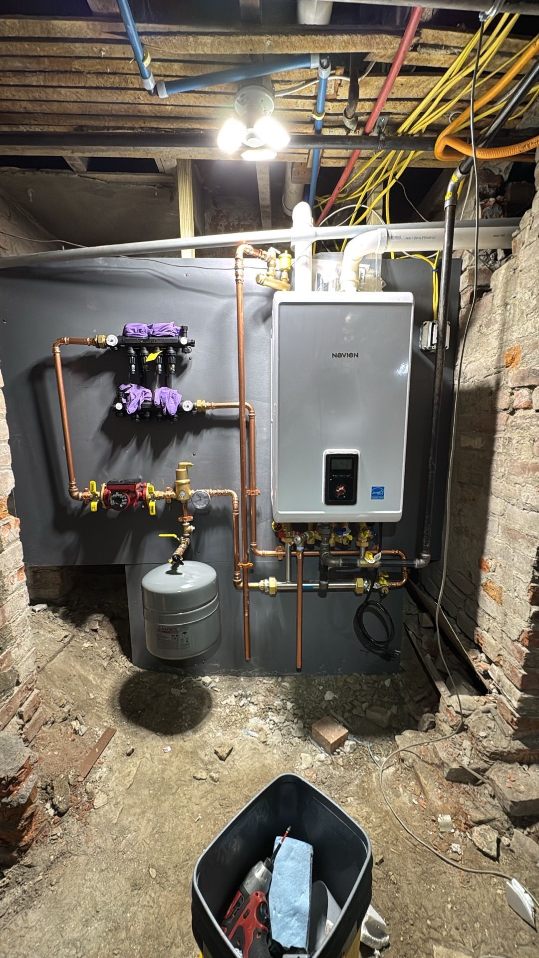 Basement utility room with water heater, boiler, pipes, and exposed ceiling beams.