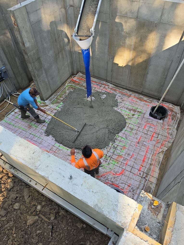 Workers pouring concrete into a foundation trench at a construction site