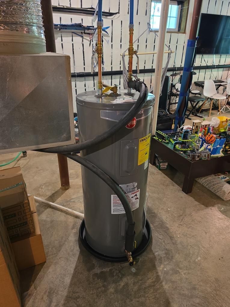 Gray industrial water heater with pipes and hoses in a workshop or utility room