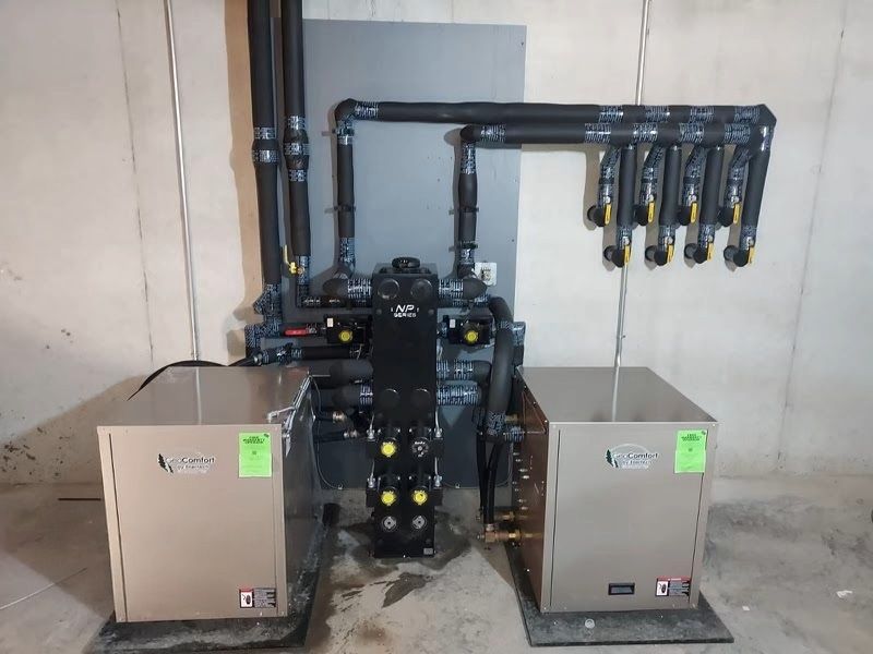 Industrial water filtration system with black pipes and two beige cabinets against a wall