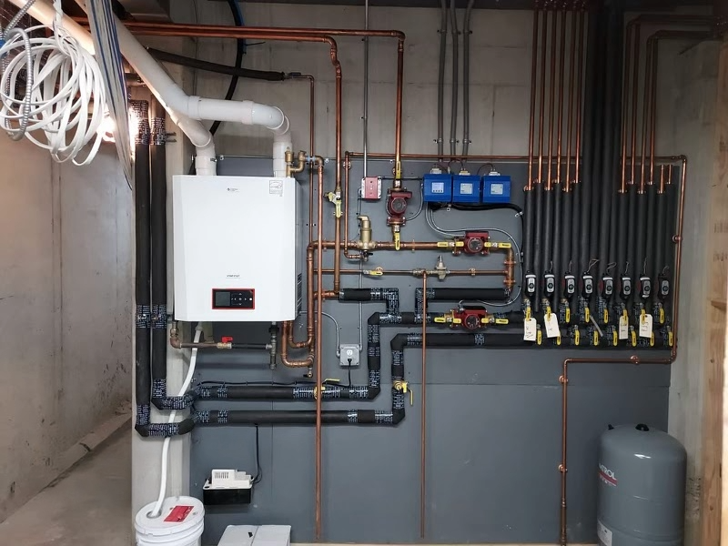 Basement utility wall with boiler, pipes, valves, and electrical wiring in an unfinished room