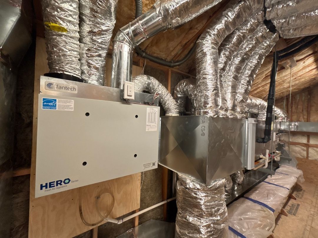 HVAC ductwork and two metal air-handling units installed in an unfinished attic space
