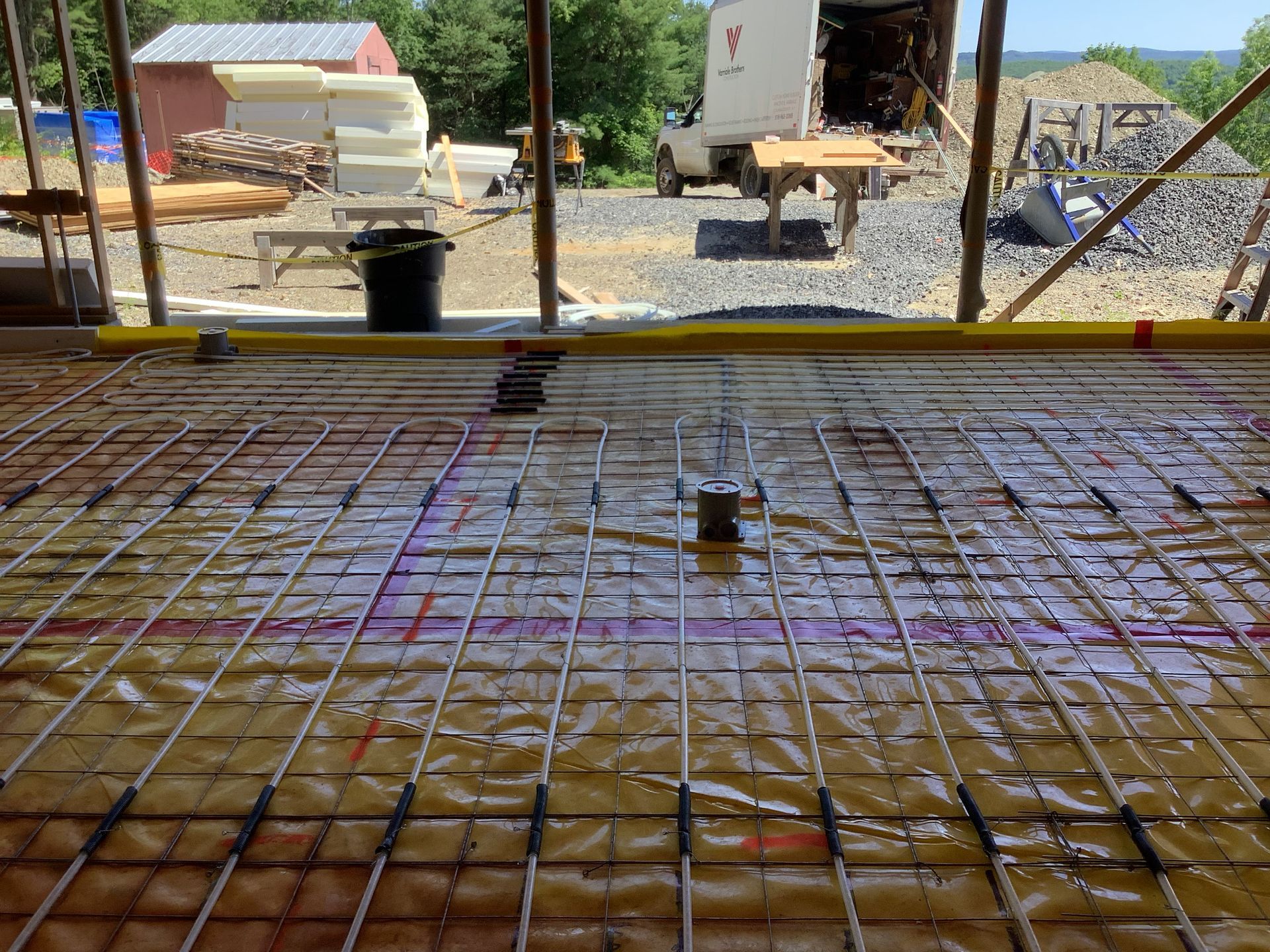 Construction site with rebar grid and concrete floor under formwork, viewed through a wall opening