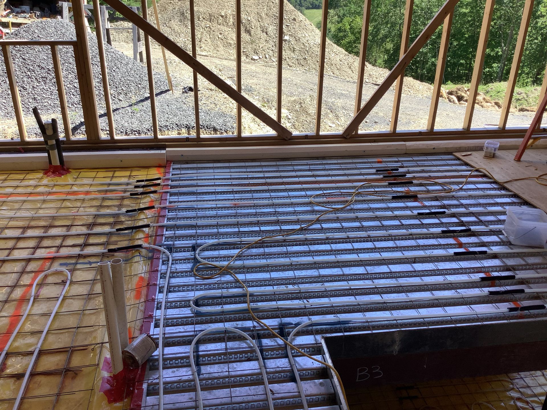 Rusty metal grating and a blue-covered floor section on a construction site, with railings in the background