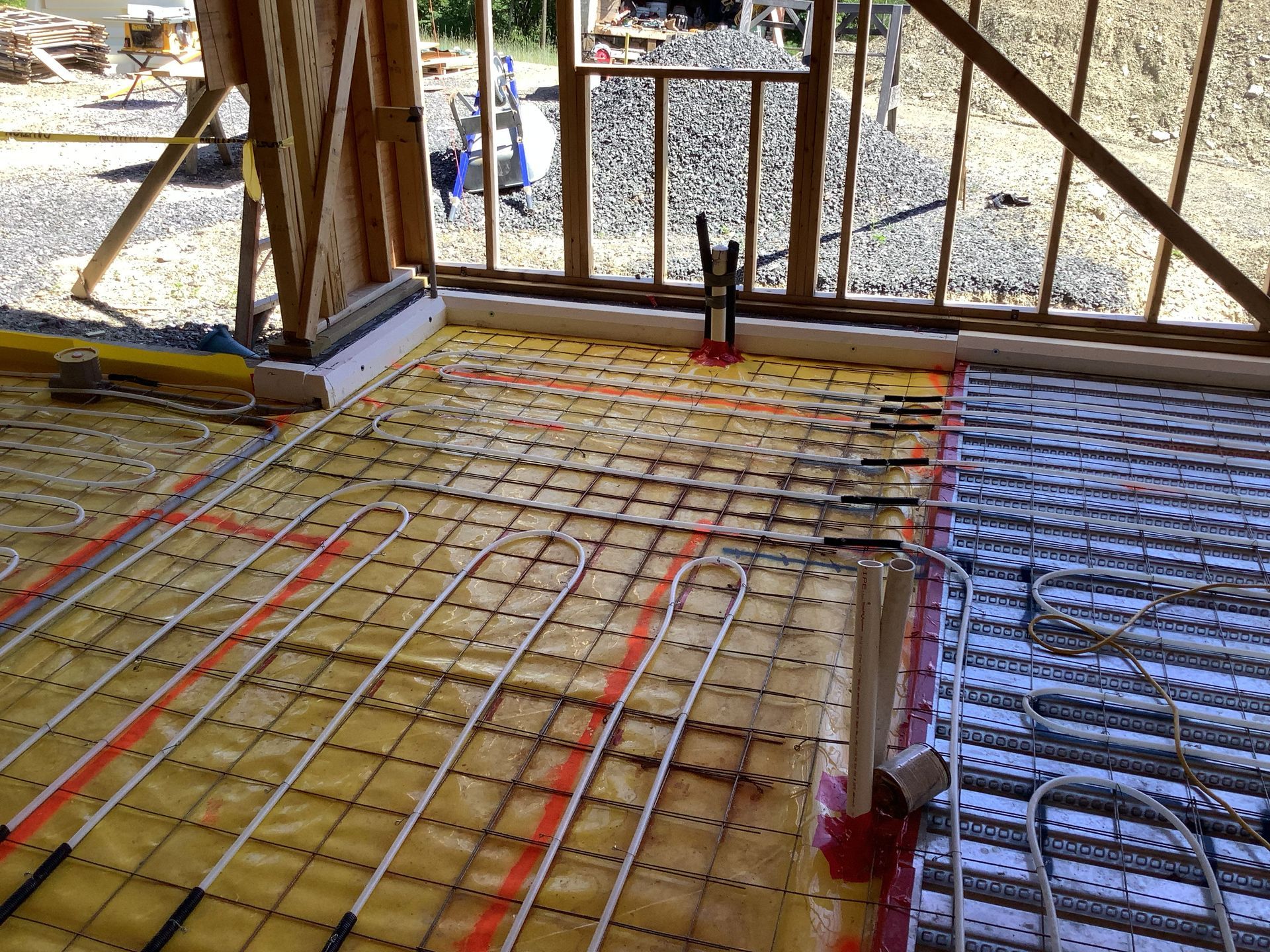 Construction site with rebar and tubing laid over a floor slab in a framed building shell