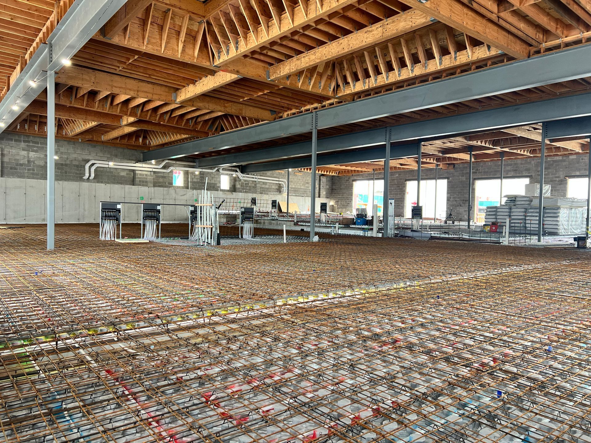 Empty indoor hall with exposed wooden roof trusses and rows of chairs on a patterned floor