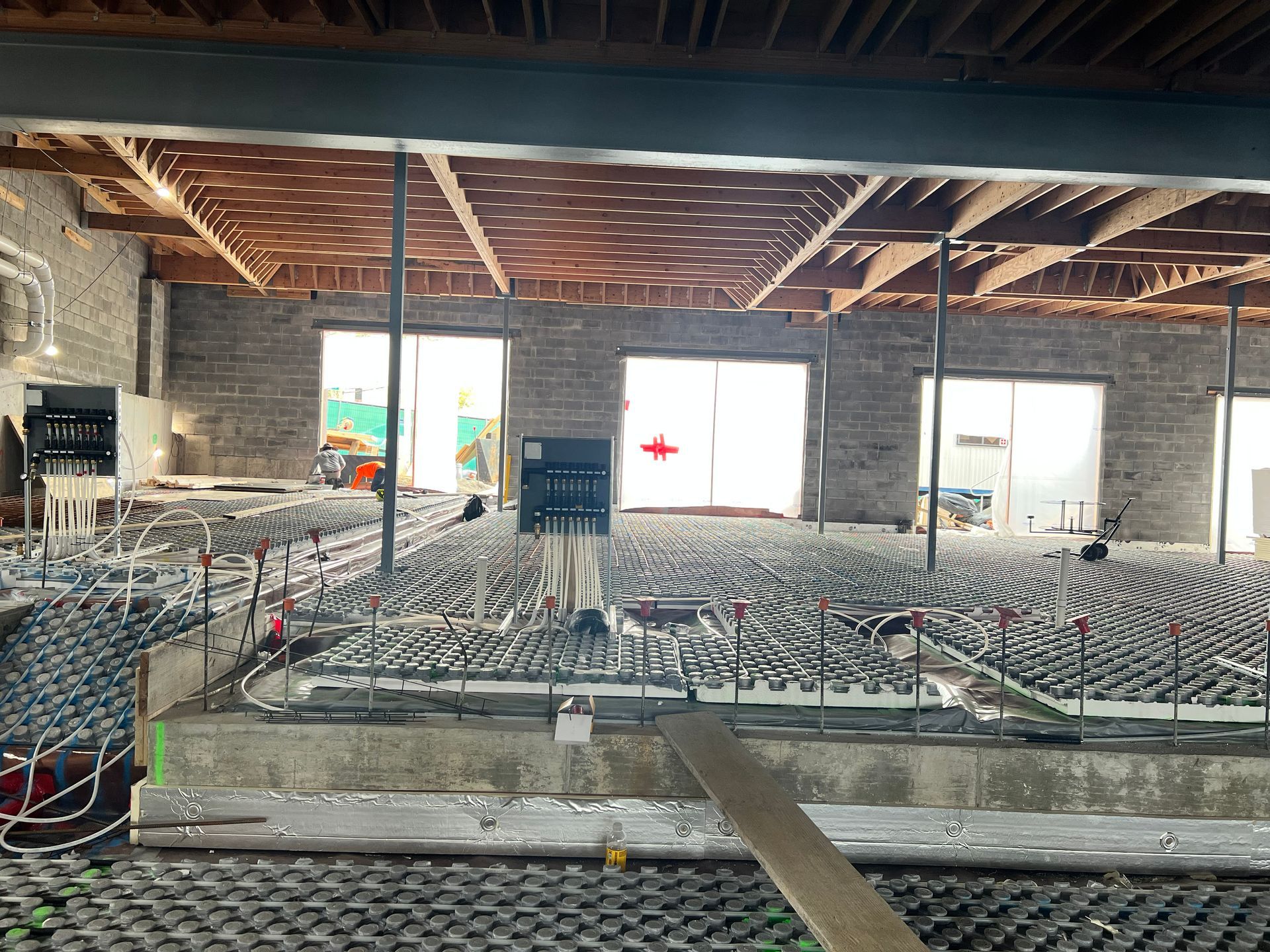 Large interior hall with rows of folding chairs, exposed ceiling beams, and daylight through open windows.