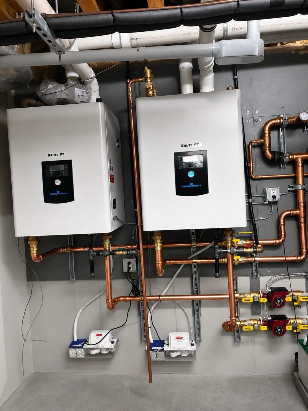 Wall-mounted white boiler units with copper piping in a utility room