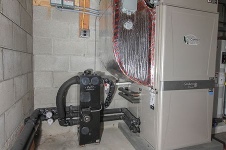 Basement utility room with boiler, pipes, and insulated tanks against cinder block walls