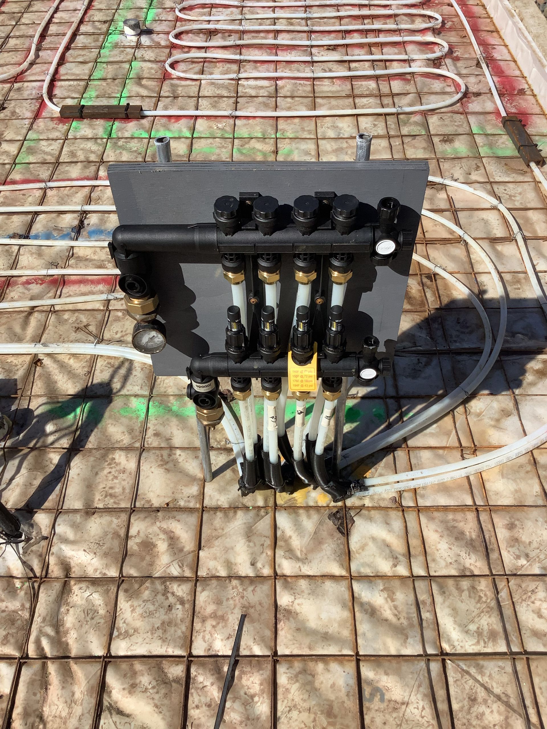 Black electrical control box with wiring and hoses mounted on a tiled surface outdoors