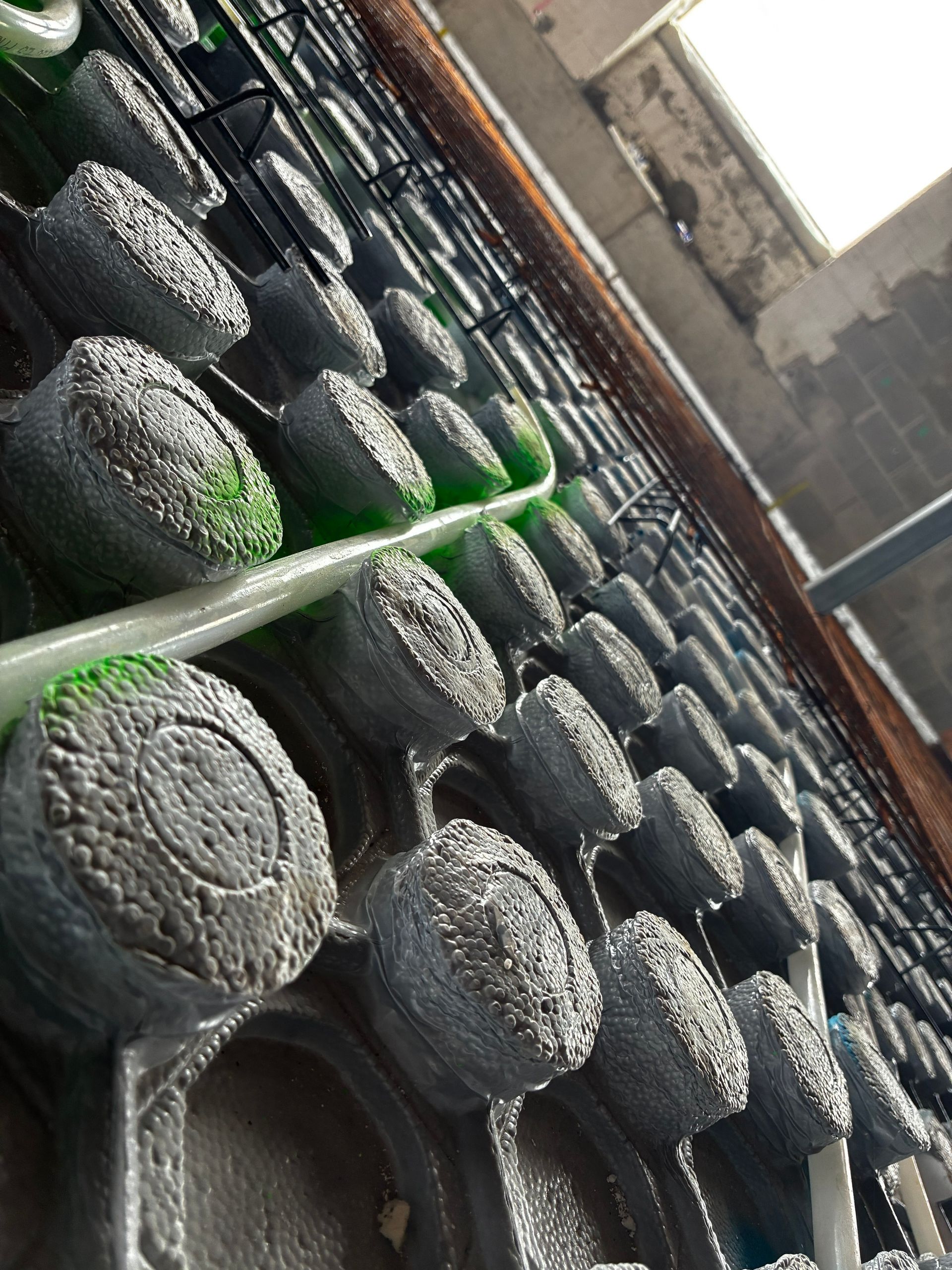 Rows of dark cylindrical rolls drying outdoors, with a green pole in the foreground.