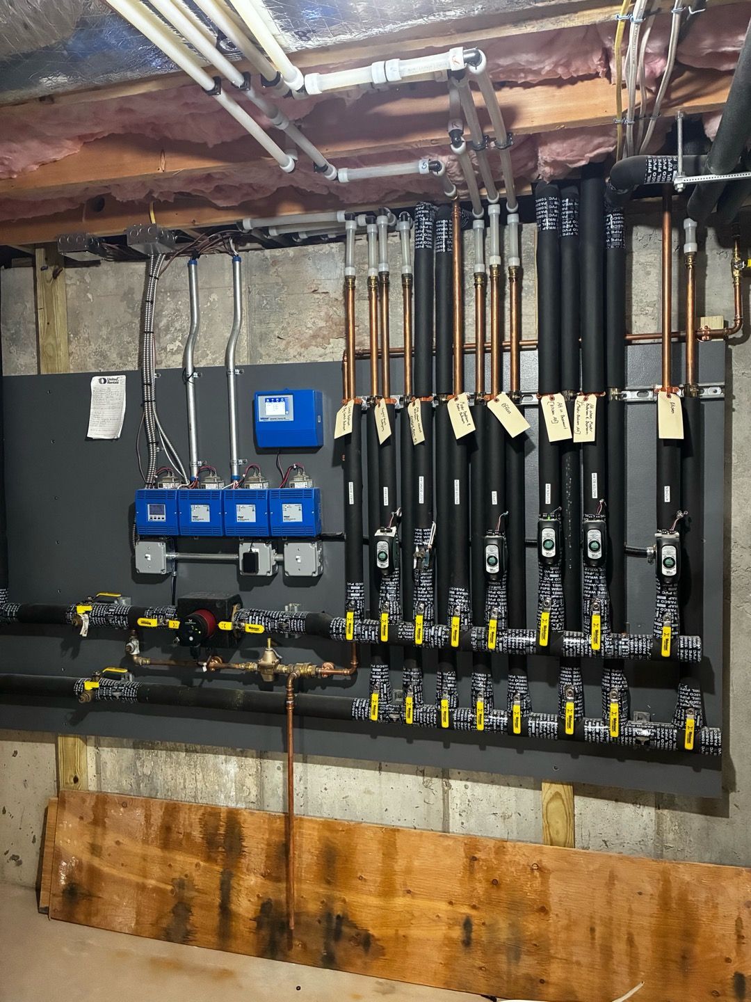 Electrical meter and breaker panel with multiple black shutoff switches in a basement utility room.