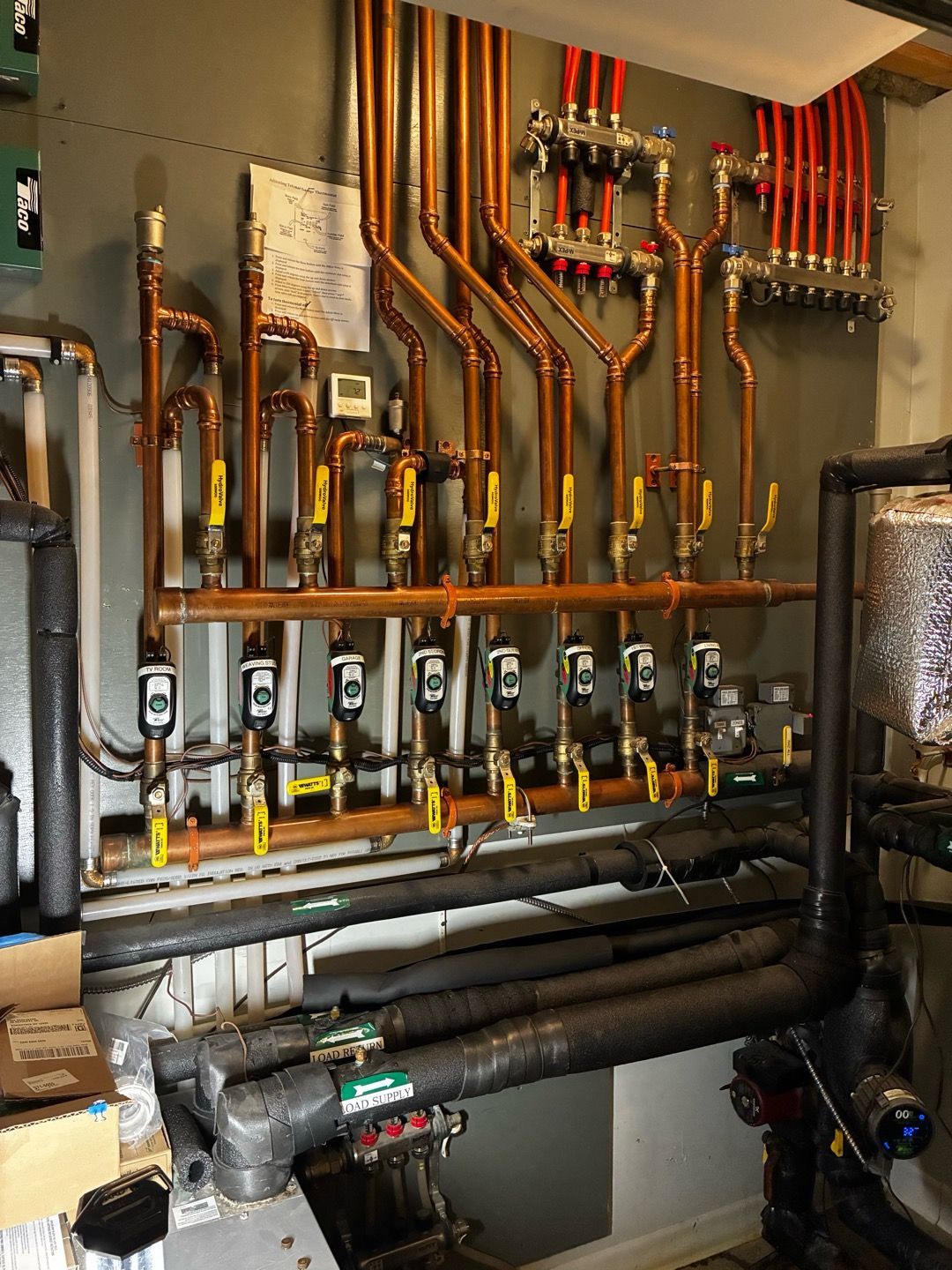 Boiler room with exposed copper pipes, valves, and insulated plumbing on a wall
