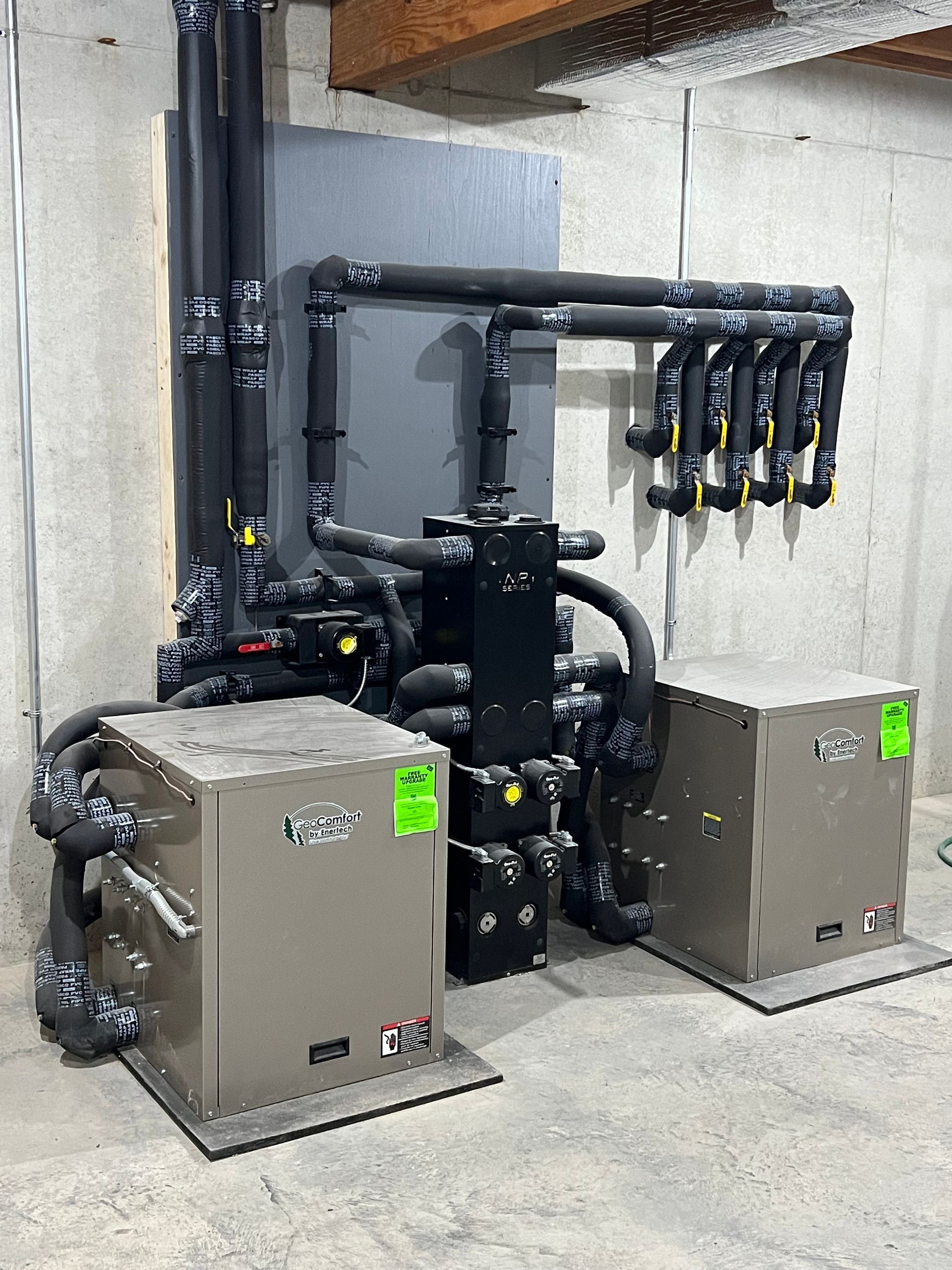 Industrial HVAC/mechanical equipment with pipes and two beige units in a utility room