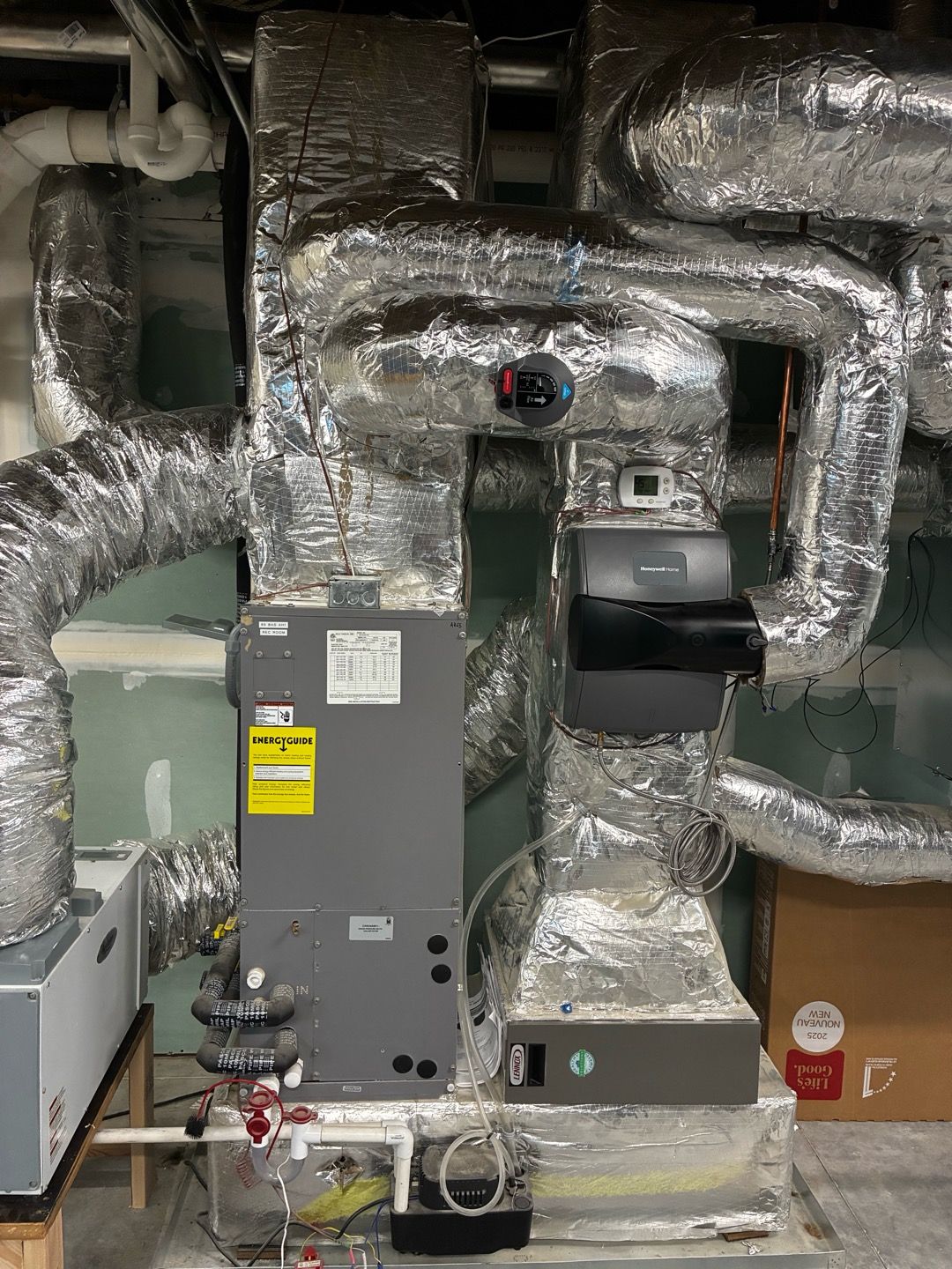 Foil-wrapped HVAC ducts and a gray furnace in a utility room
