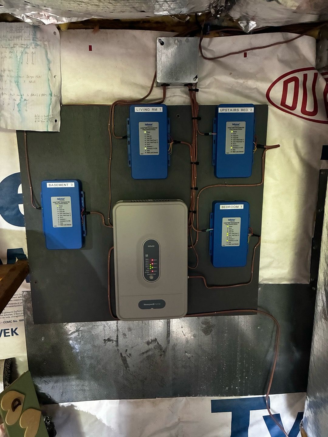 Electrical control panel with four blue modules and a gray central unit mounted on a wall.
