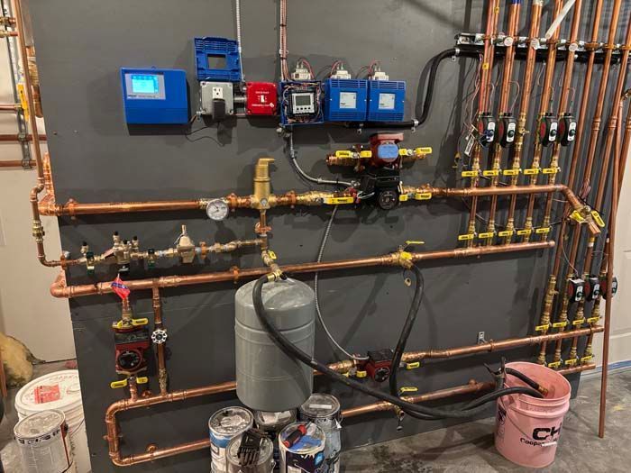 Copper plumbing and wall-mounted control boxes for a heating system in a basement utility area