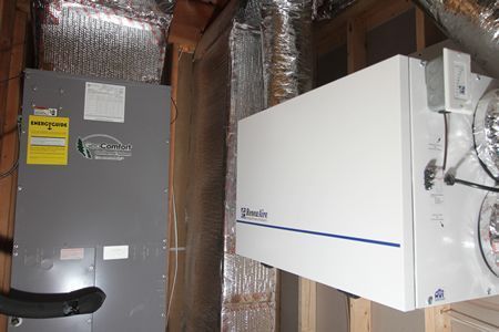 Two wall-mounted HVAC units in a basement with exposed ductwork and insulated pipes