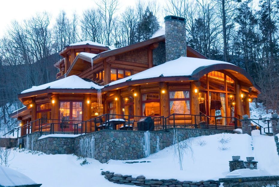 Snow-covered rustic lodge glowing with warm lights in a winter forest at dusk