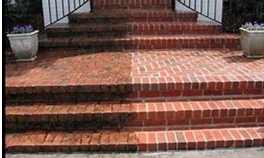 Half-cleaned red brick steps, showing the contrast after pressure washing.