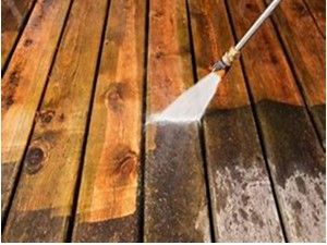 Pressure washing wooden deck, removing dirt and grime, revealing clean wood.