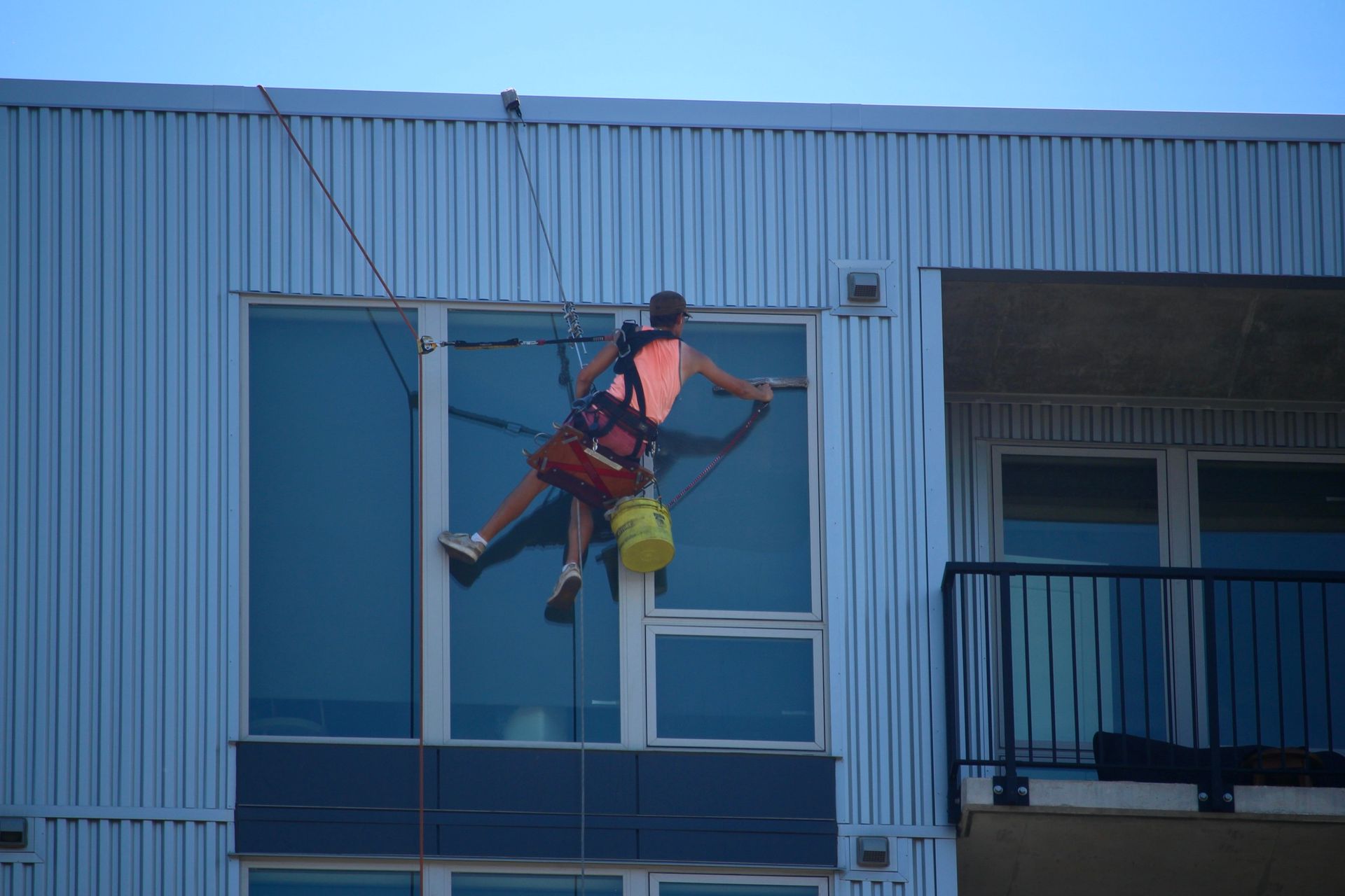 A man is cleaning a window on the side of a building.