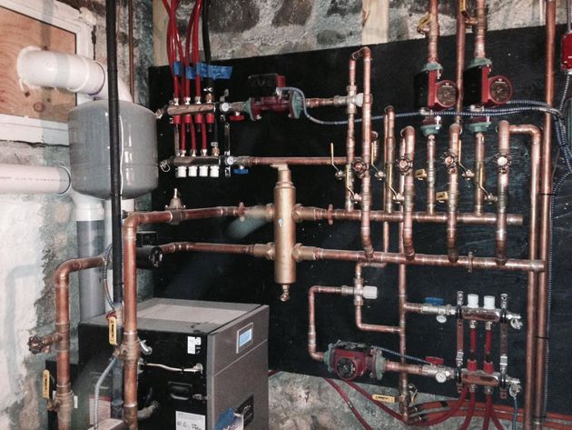 Basement boiler and copper pipe manifold with valves and pumps in a mechanical room