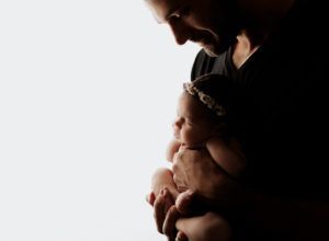 A man is holding a newborn baby in his arms.