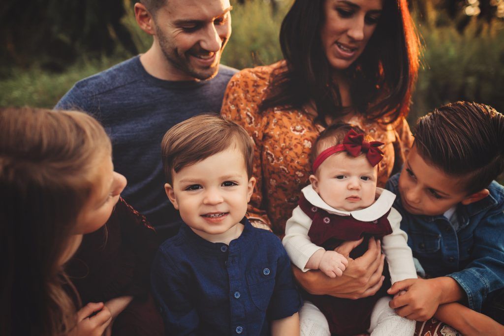 A family is posing for a picture together in a park.