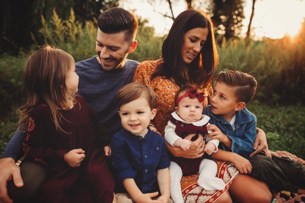 A family is sitting on a blanket in the grass.