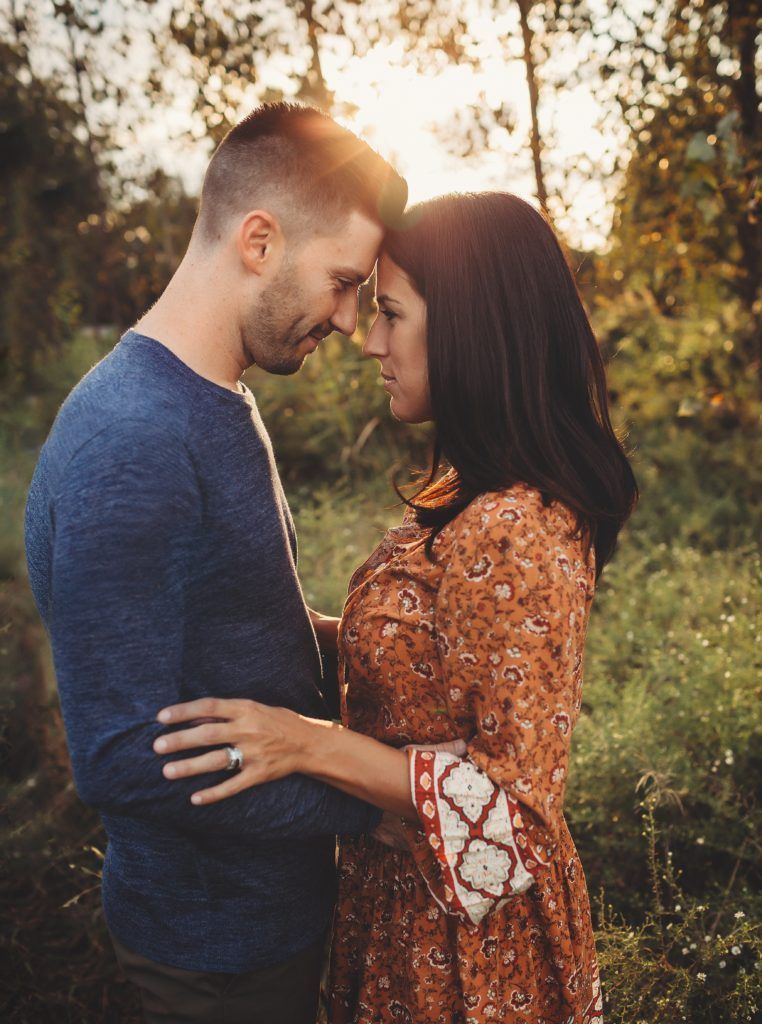A man and a woman are looking at each other in the woods.