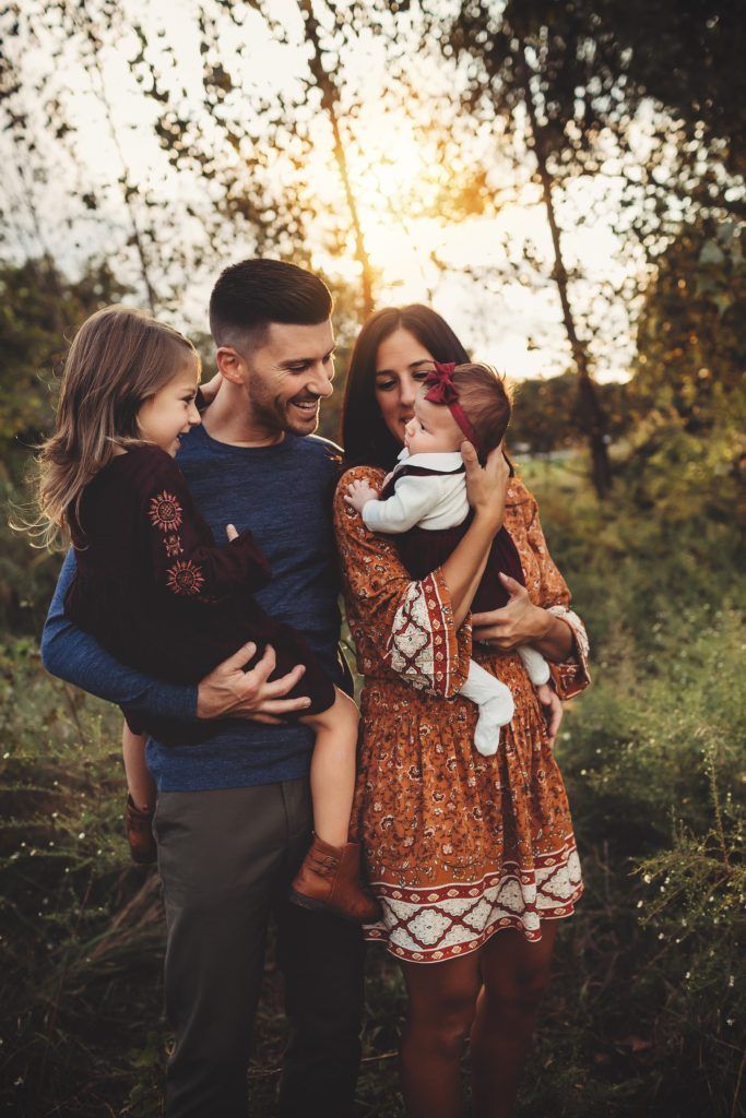 A family is posing for a picture in the woods.